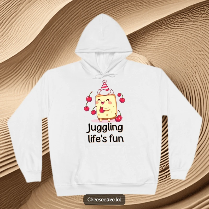 Funny cheesecake juggler hoodie showing a cheesecake wearing a party hat and juggling cherries, radiating joy.
